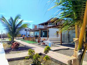 a house with palm trees in front of it at Bella Vista condominio in Canoas De Punta Sal