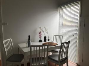 a dining room table and chairs with a white table and a bottle of wine at Whitening Cottage in Tumbarumba