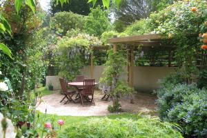 a patio with a table and chairs in a garden at McAuley Glen Boutique B&B in Dunedin