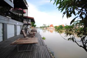 a row of benches sitting on a dock next to a river at Baan Keang Chon Ayutthaya บ้านเคียงชล อยุธยา in Phra Nakhon Si Ayutthaya