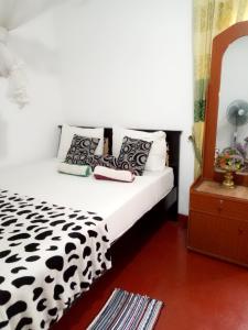 a bed with black and white pillows and a mirror at Tunnel Gap Homestay in Ella
