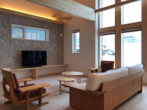 a living room with a couch and a tv at Tsuru Apartments in Furano