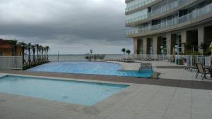 a swimming pool next to a building with palm trees at O local para o seu lazer in Santos