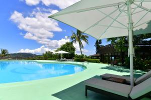 a swimming pool with a white umbrella and a chair at Coco Garden Resort Okinawa in Uruma