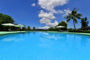 a large blue swimming pool with two white umbrellas at Coco Garden Resort Okinawa in Uruma