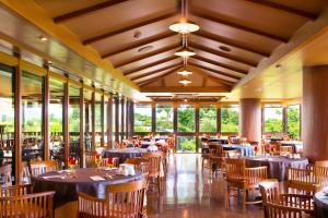 a dining room with tables and chairs and windows at Coco Garden Resort Okinawa in Uruma