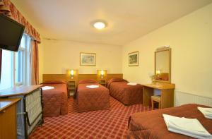 um quarto de hotel com três camas e uma televisão em Seymour Hotel em Londres