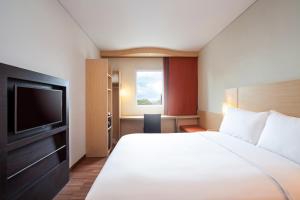 a hotel room with a bed and a television at Ibis Makassar City Center in Makassar