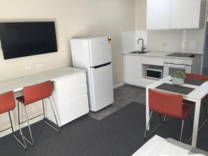 uma cozinha com um frigorífico branco e cadeiras vermelhas em Bega Village Motor Inn em Bega