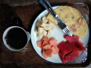 a plate of food with fruit and a cup of coffee at Black Marlin - Kadidiri in Batudaka