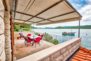 eine Terrasse mit einem Tisch und Stühlen sowie Blick auf das Wasser in der Unterkunft Holiday Home Gluscevic in Klek