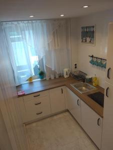 d'une cuisine avec des placards blancs, un évier et une fenêtre. dans l'établissement Apartament Blanka, à Varsovie