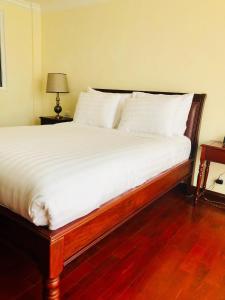 1 dormitorio con 1 cama grande con sábanas blancas en Phasouk Vien Chantra Hotel, en Vientiane