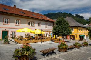 a town with benches and tables and yellow umbrellas at JUFA Hotel Murau in Murau
