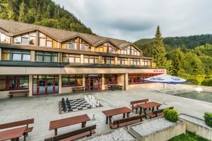 un grande edificio con panchine e ombrellone di JUFA Hotel Grünau im Almtal a Grünau im Almtal