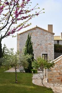a stone building with flowering trees in front of it at Achelatis Traditional Guest Houses in Areopolis