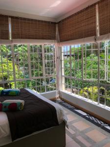 a bedroom with a bed and large windows at Villa Sirandane in Baie du Tombeau