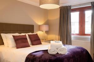 ALTIDO Elegant 2 bed, 2 bath flat, patio and free parking في إدنبرة: غرفة نوم عليها سرير وفوط