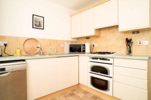 cocina con armarios blancos y lavavajillas en JOIVY Elegant 2 bed, 2 bath flat, patio and free parking en Edimburgo
