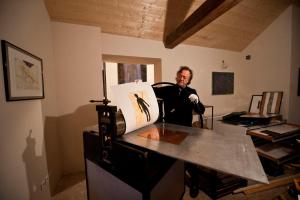 Un hombre sentado en un escritorio con una pintura. en Les Arts Verts en Kruth