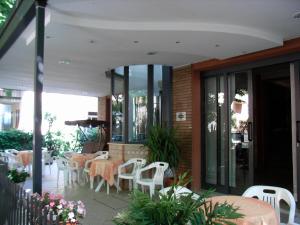 um restaurante com cadeiras brancas e mesas num pátio em Hotel Eureka em Rimini