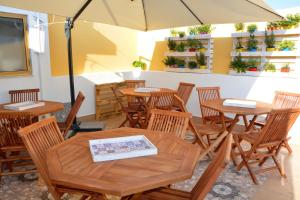 a restaurant with wooden tables and chairs with an umbrella at B&B Micucco in Milazzo
