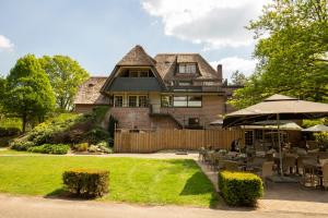 een huis met een tuin met tafels en stoelen bij Fletcher Hotel Restaurant De Wipselberg-Veluwe in Beekbergen