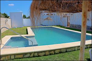 a swimming pool in a yard with an umbrella at Chalet Ruperto in Conil de la Frontera