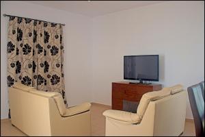 a living room with two chairs and a flat screen tv at Chalet Ruperto in Conil de la Frontera +29 photos