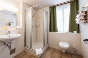 ein Badezimmer mit Dusche, Toilette und Waschbecken in der Unterkunft JUFA Hotel Grundlsee in Grundlsee + 35 Fotos