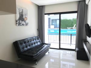 eine schwarze Ledercouch in einem Wohnzimmer mit Pool in der Unterkunft V.O.P Suite in Chaweng