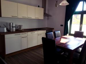 a kitchen with a wooden table and white cabinets at Ferienwohnung Alabama in Lutherstadt Wittenberg +13 photos