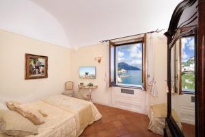 a hotel room with a bed, tv and a painting on the wall at Villa Alba d'Oro - Historic Luxury Villa in Amalfi