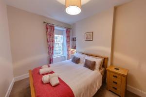 a bedroom with a bed with a red blanket and a window at ALTIDO Stylish Apartment in Trendy New Town Location in Edinburgh