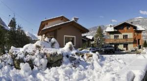 a house covered in snow in front of a house at Au Petit Chevrot in Aosta