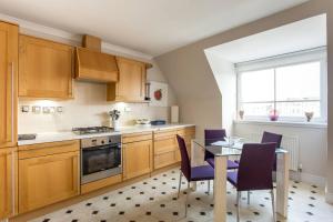 エディンバラにあるALTIDO Homely Apartment near Leith Walkのキッチン(木製キャビネット、テーブル、椅子付)