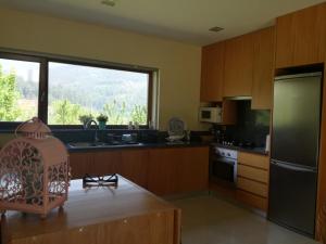 a kitchen with wooden cabinets and a large window at Cottage, Casa do Laranjal - Near Gerês in Geres