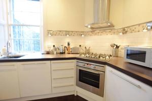 a kitchen with white cabinets and a microwave oven at JOIVY Modern City Centre Flat next to Calton Hill in Edinburgh +7 photos