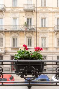 un planteur de fleurs rouges devant un bâtiment dans l'établissement A due passi da tutto, à Turin