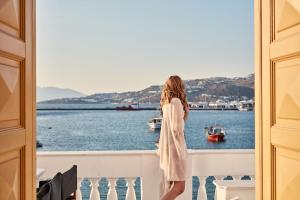 a woman standing on a balcony looking out at the water at Villa Kampani Sea View Villa Mykonos Town in Mikonos