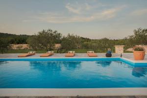 a large swimming pool with lounge chairs in a yard at Villa Red Hacienda with Pool in Vodice