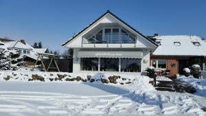ein Haus mit Schnee auf dem Boden davor in der Unterkunft Meeresblick Ferienwohnung in Husum