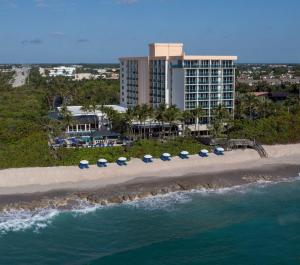 eine Luftansicht auf einen Strand mit Sonnenschirmen und ein Hotel in der Unterkunft Jupiter Beach Resort & Spa in Jupiter
