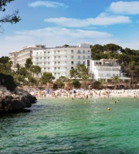 a group of people on a beach in the water at Hotel Apartamentos Cala Santanyi in Cala Santanyi