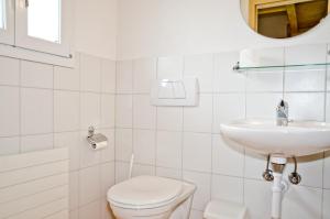 ein weißes Bad mit einem WC und einem Waschbecken in der Unterkunft Apartment Kiwi rechts - GRIWA RENT AG in Grindelwald