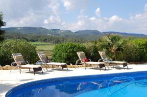 - un groupe de chaises assises à côté de la piscine dans l'établissement Arianel.la B&B Penedes, à Torrellas de Foix
