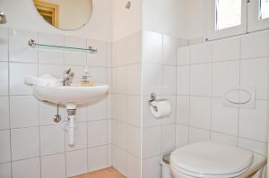 Baño blanco con aseo y lavamanos en Apartment Kiwi links - GRIWA RENT AG, en Grindelwald