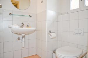 ein weißes Bad mit einem WC und einem Waschbecken in der Unterkunft Apartment Kiwi links - GRIWA RENT AG in Grindelwald