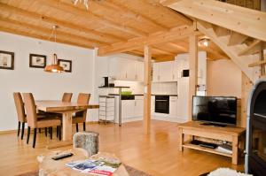 eine Küche und ein Wohnzimmer mit einem Tisch und einem TV in der Unterkunft Apartment Kiwi links - GRIWA RENT AG in Grindelwald