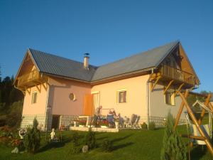 a house with two people sitting in a yard at U Edyho in Zuberec